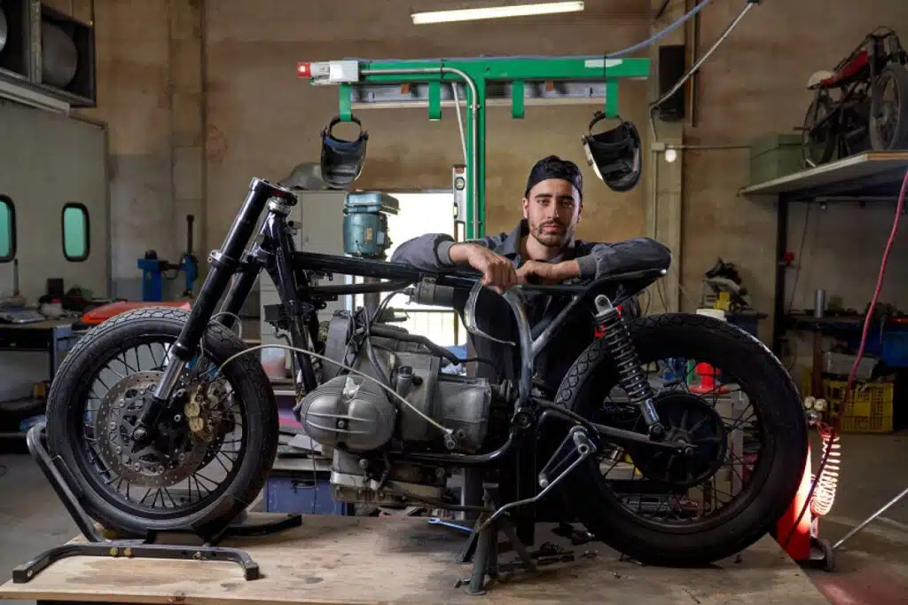 Jeune homme réparant une moto dans son garage